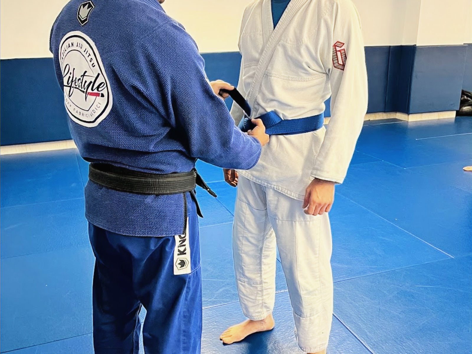 Black belt tying a blue belt on a student