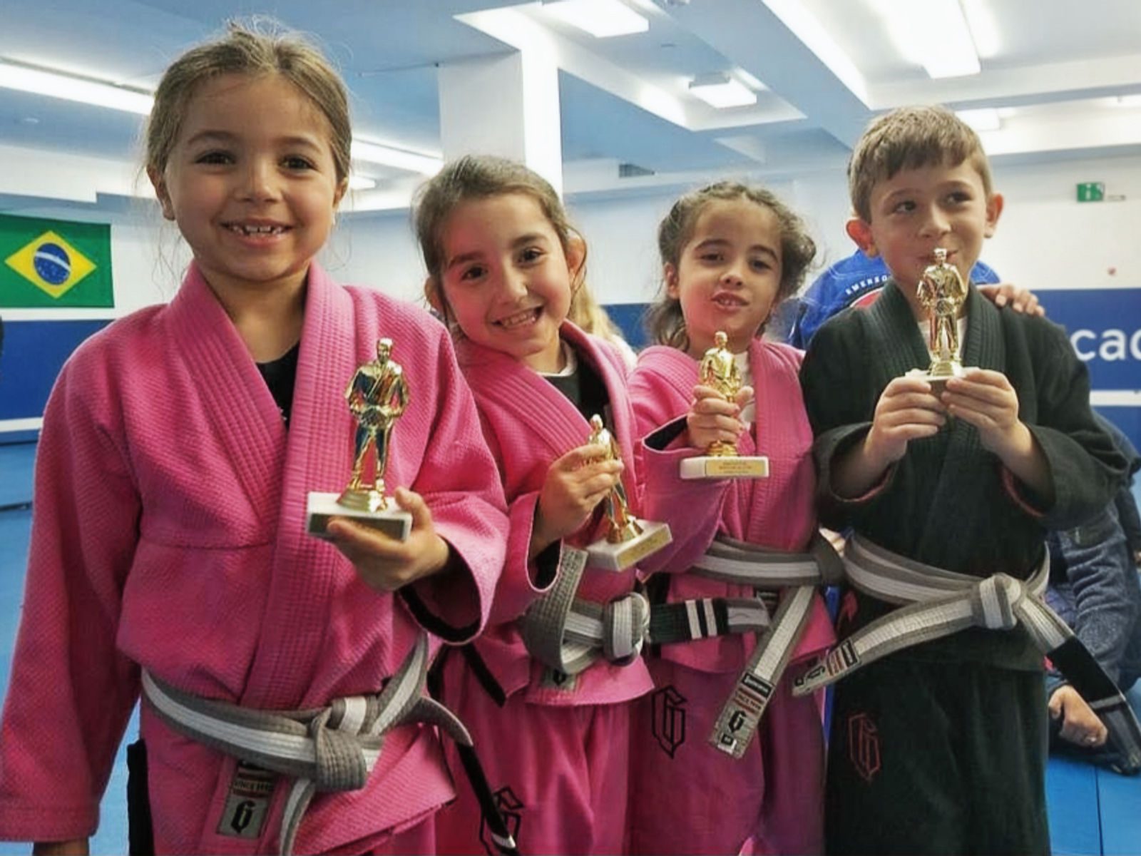Kids in pink and black gis holding trophies at Lifestyle BJJ